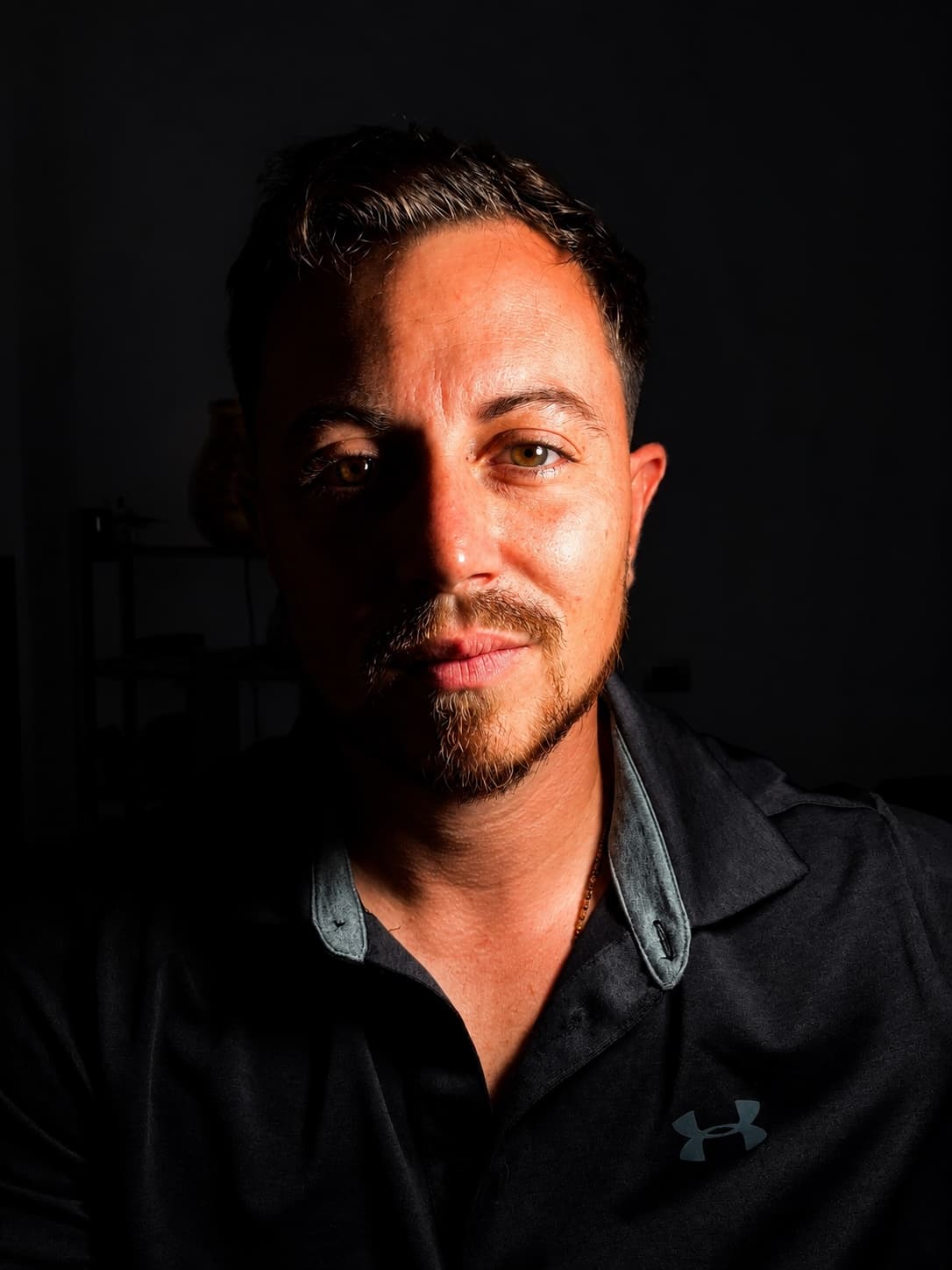 Portrait en clair-obscur d'un homme, le regard tourné vers l'objectif.