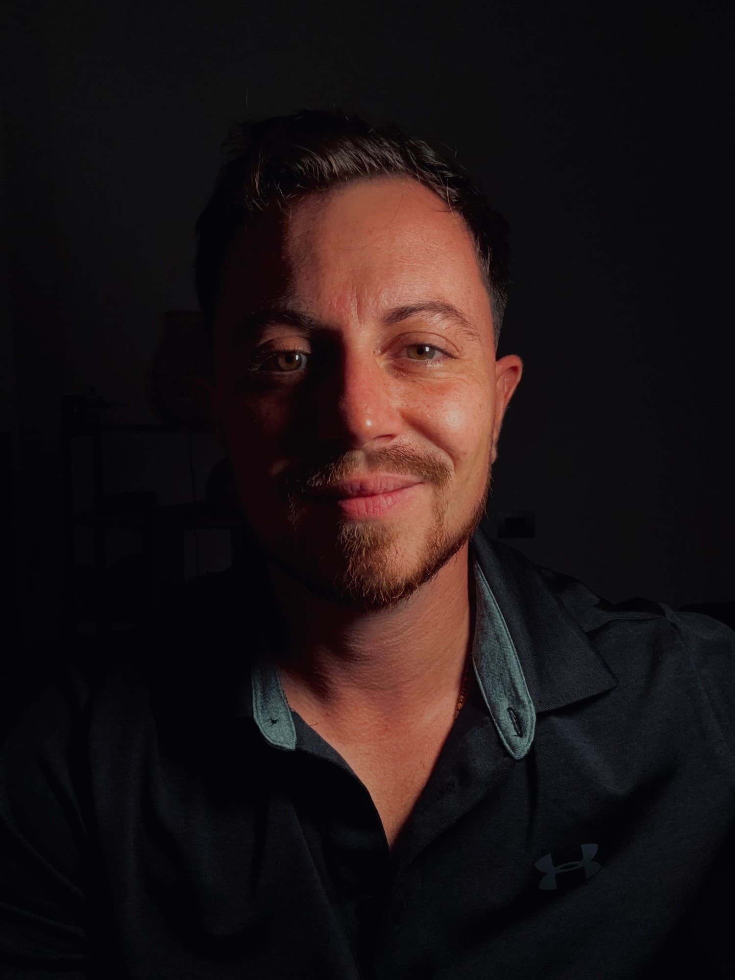 Portrait de Kilyan Del Verme, éclairé latéralement dans la pénombre.